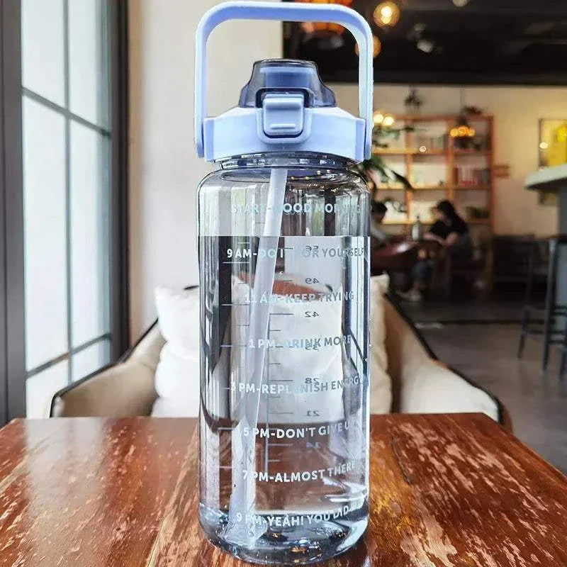 2L transparent plastic sports water bottle with straw and motivational time markers on wooden table